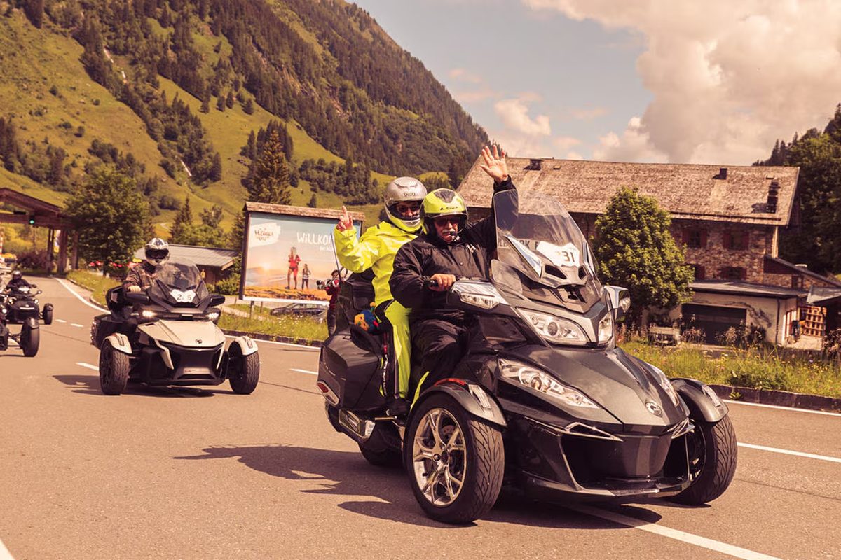Group of Can-Am three-wheel riders navigating a mountain hairpin road during a 3 Wheel Collective group ride