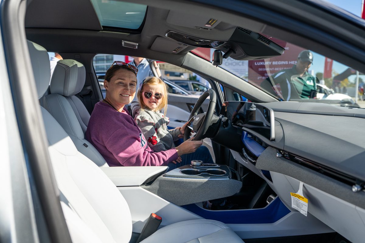 Mother and young child sitting in the driver's seat of a Cadillac Lyriq EV interior at Electrify Expo New York