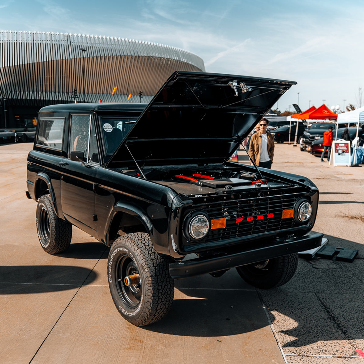 Black vintage Ford Bronco SUV with open hood at an Electrify Expo event