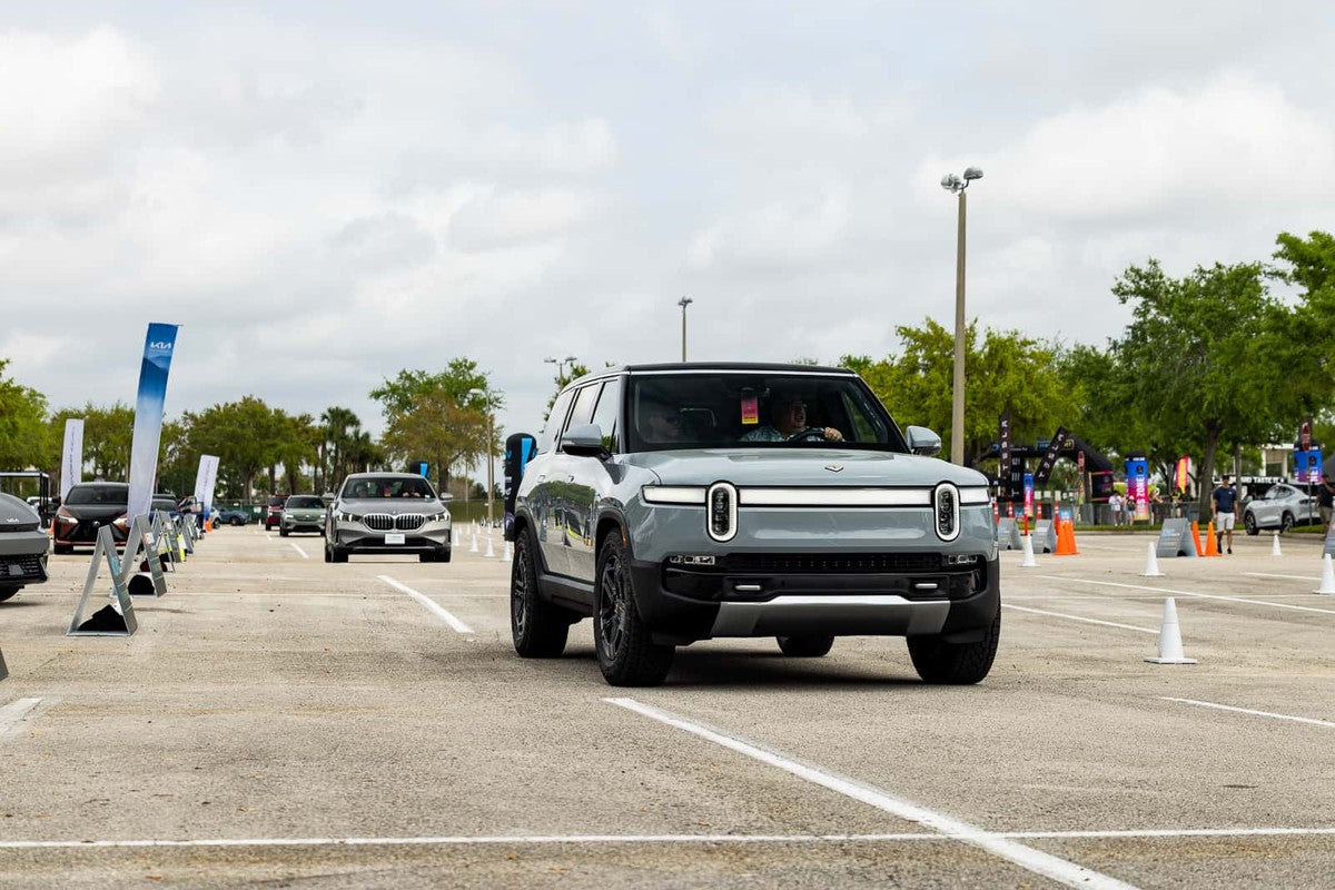 Rivian R2 electric SUV driving through a demo course during an Electrify Expo public test drive event, the platform expected to support future autonomous ride-hailing fleets and robotaxi deployments.