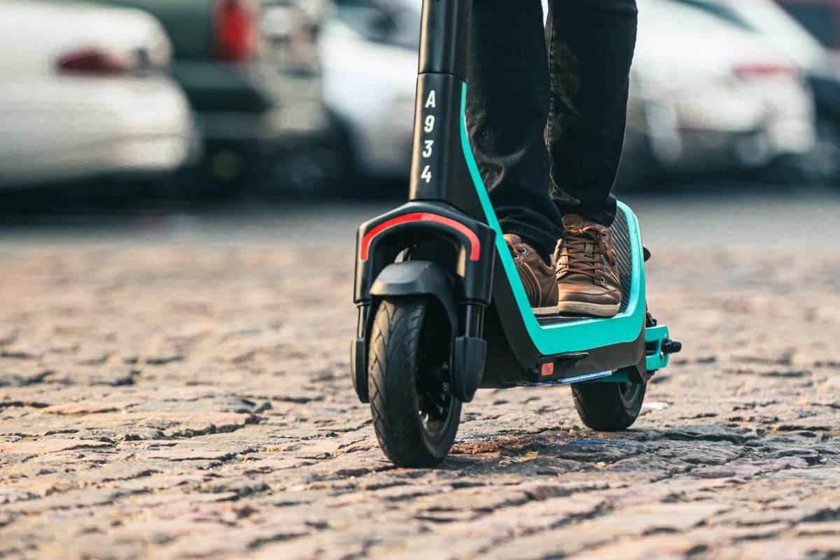 Close-up of a Veo e-scooter deck and front wheel on cobblestone