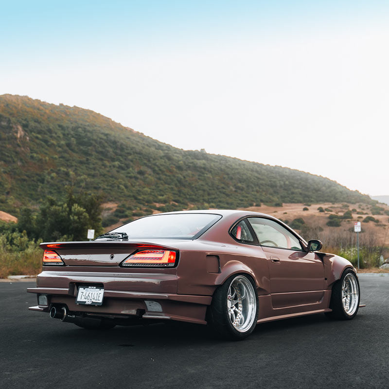 Brown JDM sports car on a road with a mountainous landscape in the background